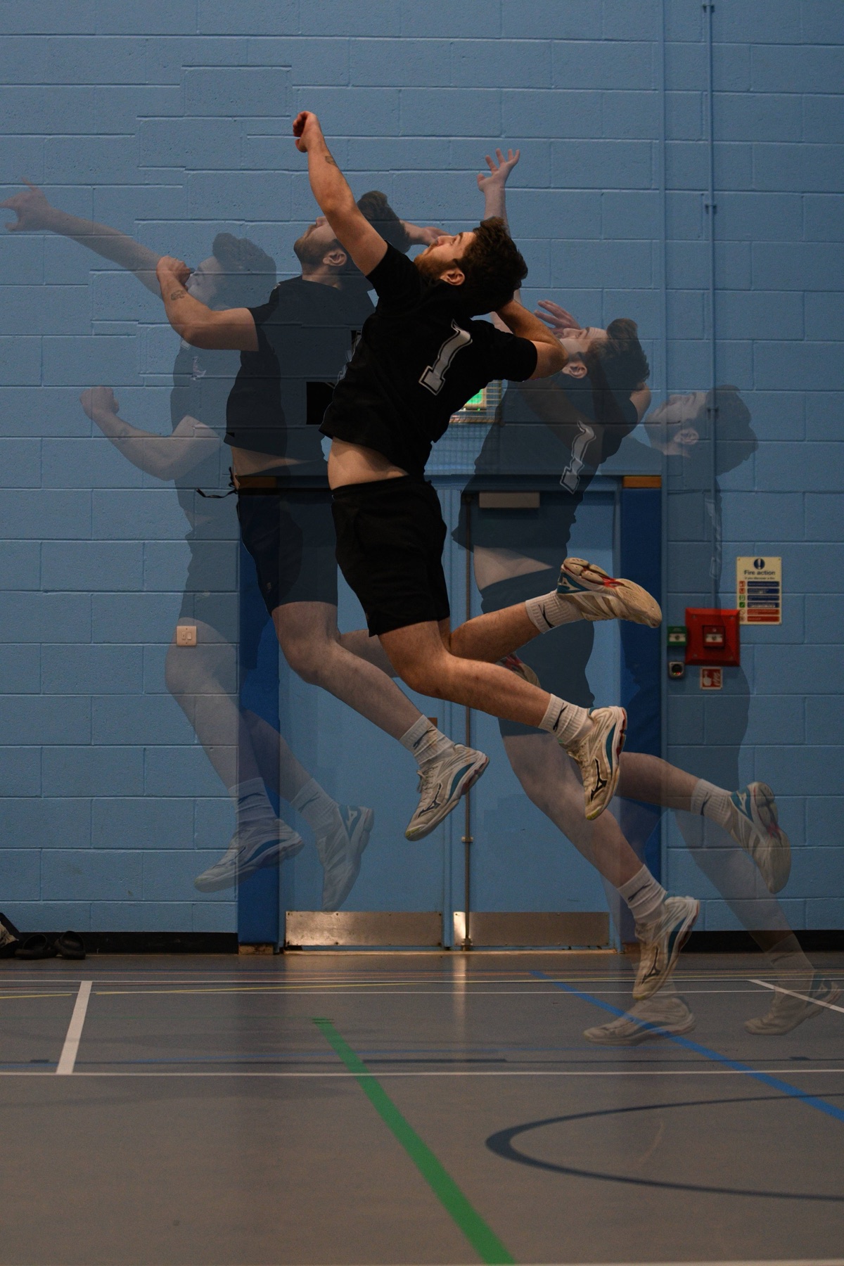 Multiple-exposure of a jump serve rising through a dark sports hall