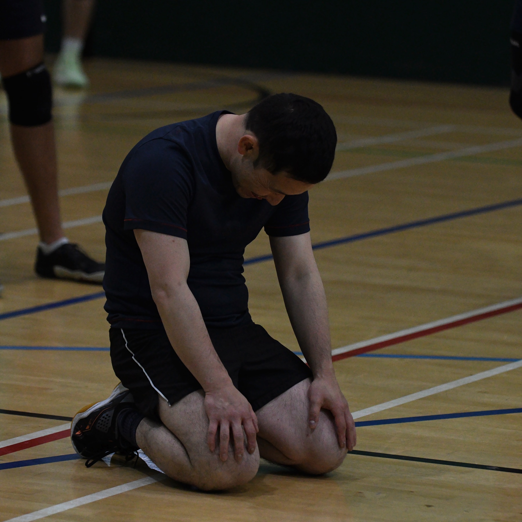 A player kneeling on the court, head bowed after the match
