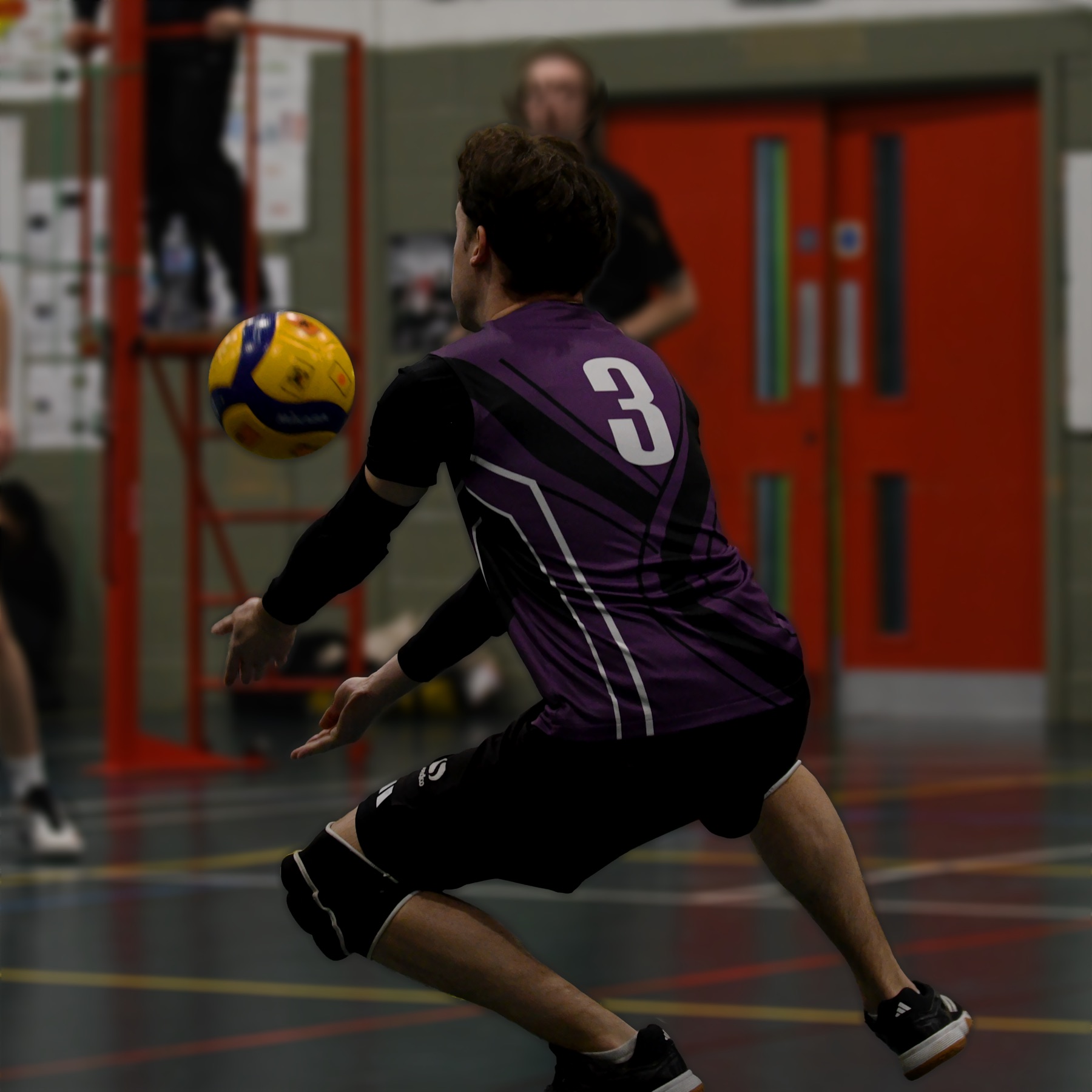 A player in purple drops low to dig the ball